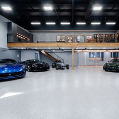 several cars are parked in an empty garage with stairs leading up to the second floor