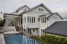 a house with a pool in front of it and a person standing on the deck