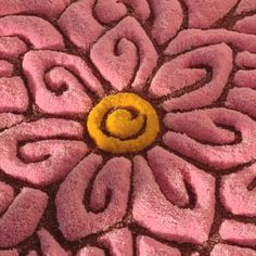 a close up of a flower with a yellow circle on it's center surrounded by pink swirls