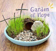 a blue bowl filled with grass and rocks on top of a wooden table next to the words garden of hope