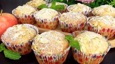 several muffins on a wooden tray next to an apple