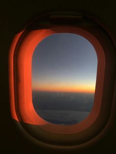 an airplane window with the sun setting in the sky as seen through it's reflection