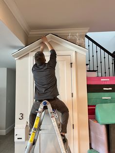 a man climbing up the side of a ladder to paint a wall in a room