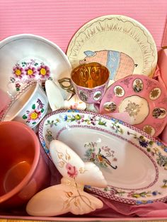 a pink box filled with lots of different colored dishes and cups on top of each other