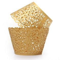 a gold cupcake wrapper with intricate cut outs on the top and bottom, sitting in front of a white background