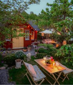 a table and chairs in the middle of a garden at night with lights shining on them