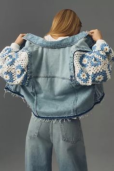 a woman is wearing a jean jacket with crocheted flowers on the sleeves and cuffs