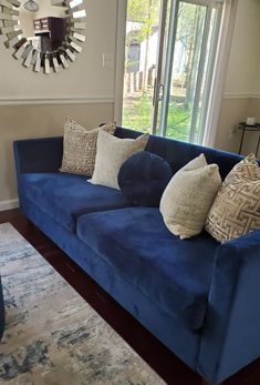 a blue couch with several pillows on it in front of a large mirror and door