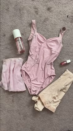 the contents of a pink swimsuit are laid out on the floor next to an empty bottle