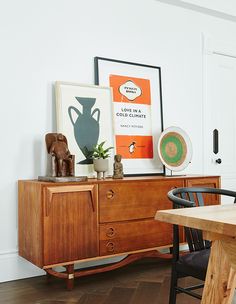 a room with a table, chair and pictures on the wall above it is shown