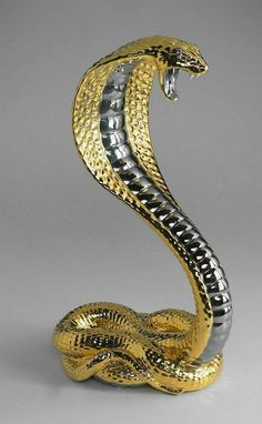 a gold and silver snake figurine sitting on top of a table