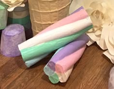 three different colored marshmallows on a table next to flowers and toilet paper