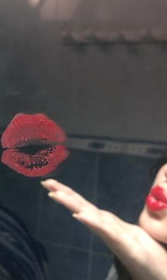 a woman with red lipstick on her lips is holding out her hand to the camera