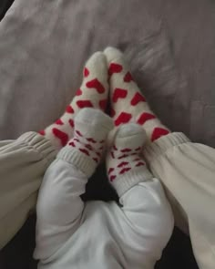 a baby laying on top of a bed wearing white and red socks with hearts on them