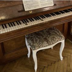 an old piano is sitting on the floor next to a bench with a footstool