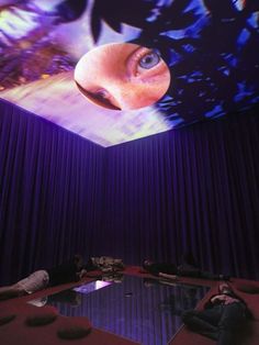 two people are sitting on the floor in front of a projection screen with an eye