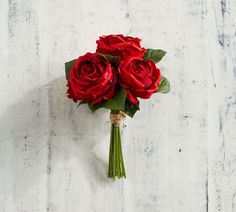 a bouquet of red roses sitting on top of a white table next to a wall