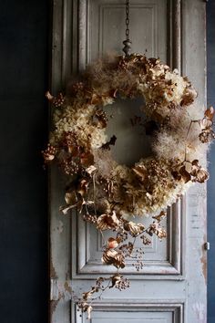 an old door with a wreath hanging from it's side and dried flowers on the front