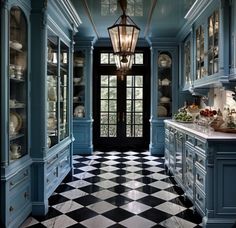 a large kitchen with blue cabinets and black and white checkered flooring on the walls