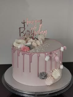 a birthday cake with pink icing and seashells