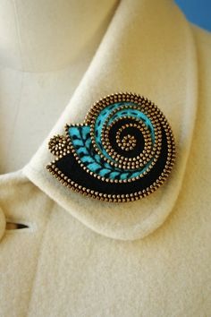 a blue and black brooch sitting on top of a white shirt neck piece,