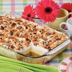 a casserole dish is sitting on a table with flowers and green napkins