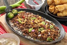 a pan filled with food sitting on top of a wooden cutting board next to other foods