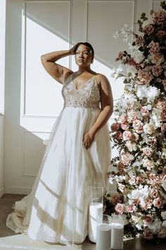 a woman in a white dress standing next to flowers