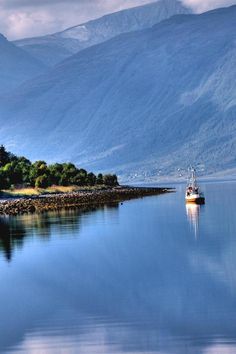 a boat floating on top of a lake surrounded by mountains