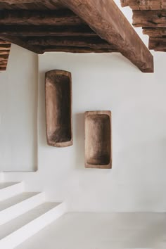 two stone niches mounted to the side of a white wall next to a set of stairs