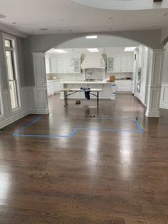 an empty room with hard wood flooring and white cabinets in the back ground area