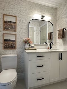 a bathroom with a toilet, sink and mirror in it's centerpieces