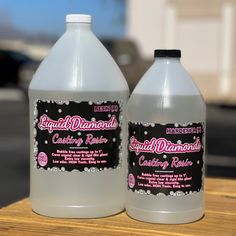 two bottles of liquid sitting on top of a wooden table