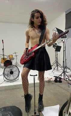 a shirtless man is playing an electric guitar