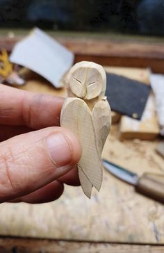 a person holding a small wooden owl on top of a table next to other woodworking tools