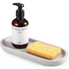 a bottle of soap next to a sponge on a tray