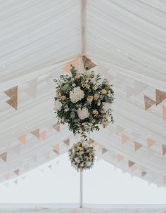 a white tent with flowers hanging from it's ceiling