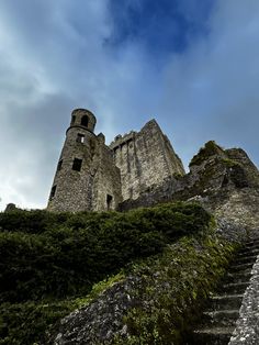 an old castle with stairs leading up to it's top and the sky in the background