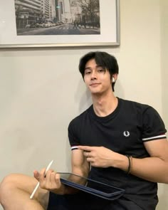 a young man sitting on the floor holding a pair of scissors in his right hand