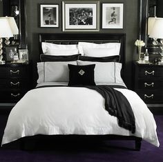 a black and white bedroom with pictures on the wall above the bed, along with two nightstands