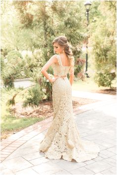 a woman in a wedding dress standing on a brick walkway with her back to the camera