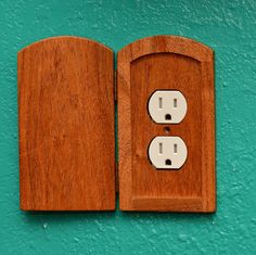 an open wooden book with two white electrical outlets on the cover, against a teal green wall