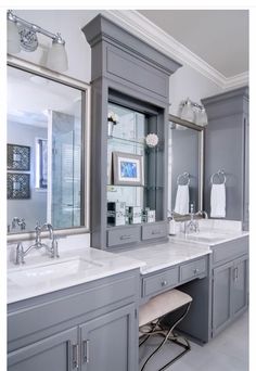 a large bathroom with two sinks and mirrors on the wall, along with gray cabinets