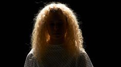 a woman with long blonde hair standing in the dark