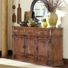 a wooden cabinet with vases and mirrors on top