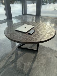 a laptop computer sitting on top of a wooden table in front of large glass windows