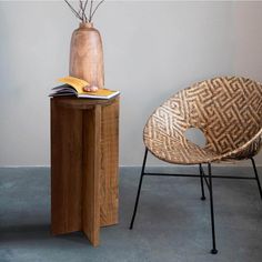 a chair next to a table with a book on it and a vase filled with flowers