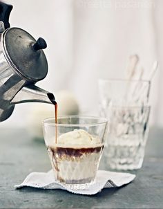 a cup filled with ice cream sitting on top of a table next to a coffee pot