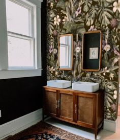 a bathroom with floral wallpaper and two sinks in front of a mirror on the wall