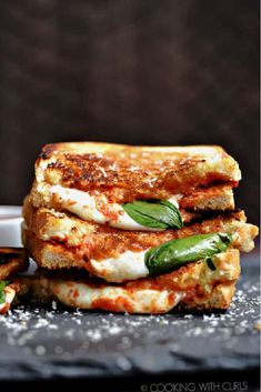 three grilled cheese sandwiches stacked on top of each other with sauce and basil leaves